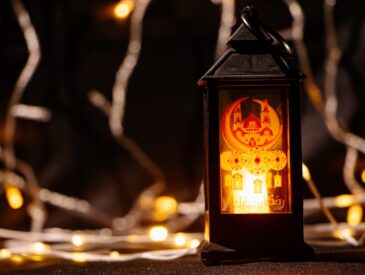 A lit lantern with festive lights in the background