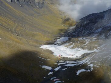 Snowy valley with rocky slopes and clouds