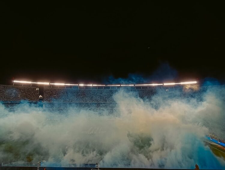 a stadium filled with lots of smoke on top of a field