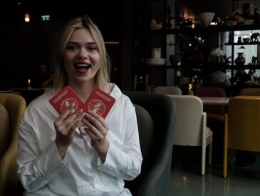 Young woman holds two red passports smiling faces cards