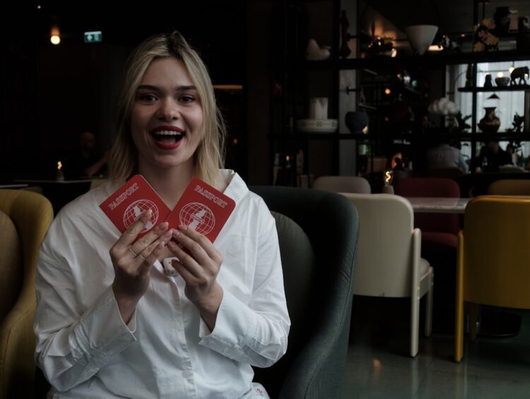 Young woman holds two red passports smiling faces cards