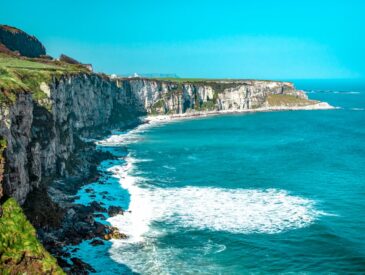 white rock cliff beside body of water'