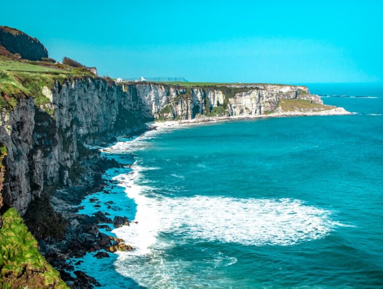 white rock cliff beside body of water'