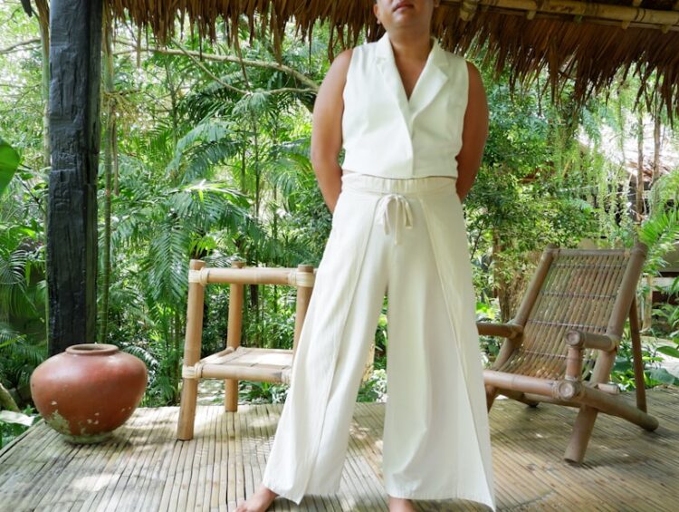 Woman in white outfit standing on a wooden porch.
