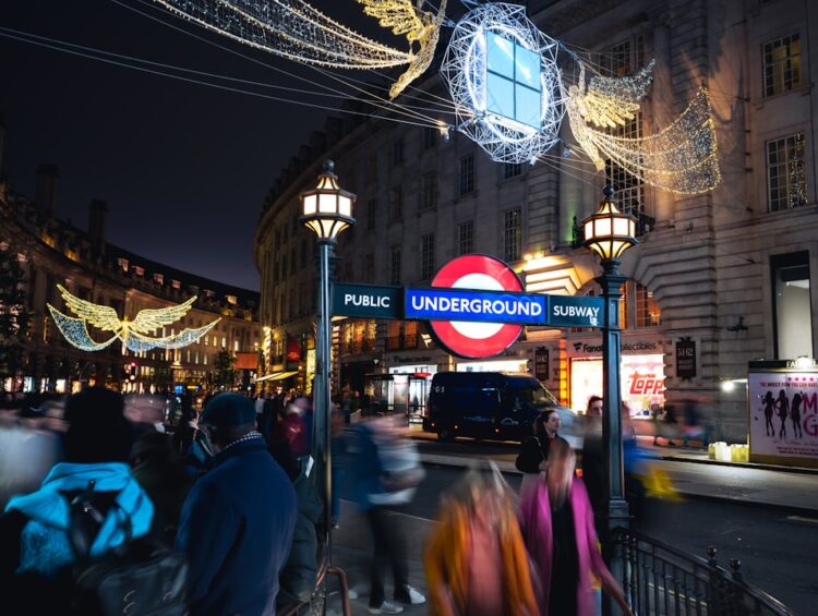 People walk past london underground entrance at night