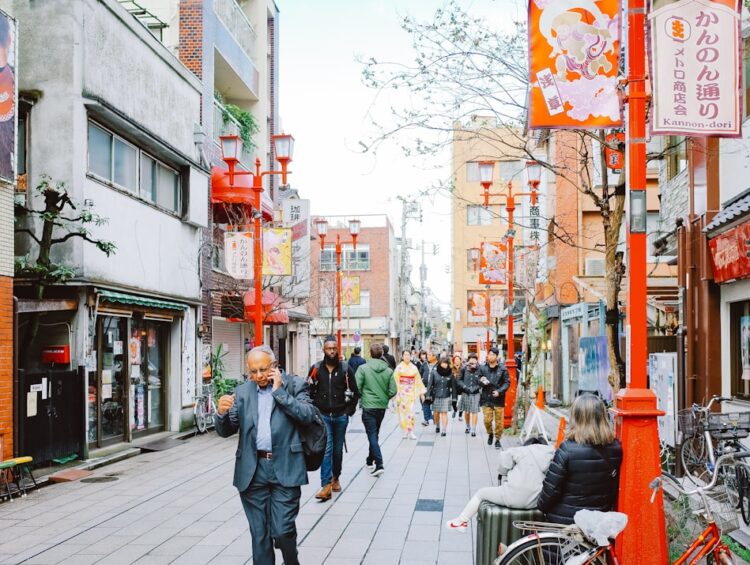People walking down a narrow street with shops and signs.